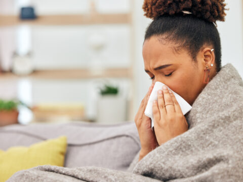 woman with allergies on her bed blowing her nose
